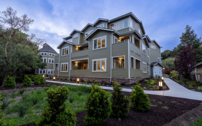 Newly constructed guestroom building at Avila Village Inn, surrounded by landscaped pathways and greenery at dusk.