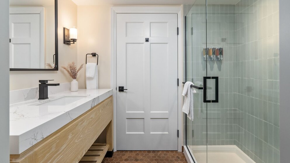 Modern guest bathroom at Avila Village Inn featuring a walk-in glass shower and sleek vanity.