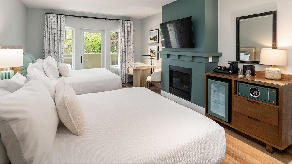 Two-queen guest room at Avila Village Inn with fireplace, private patio, and modern amenities.