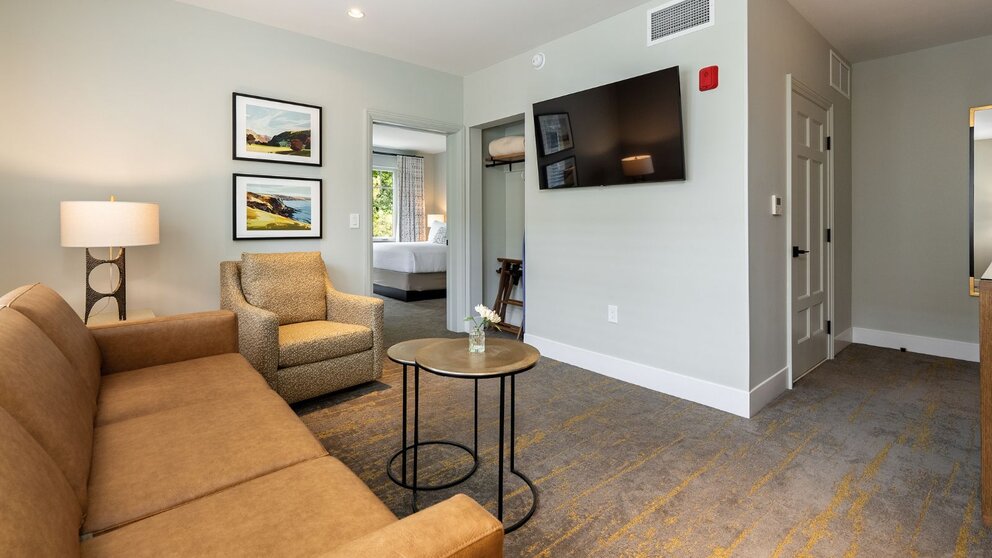 King Suite living area at Avila Village Inn with sofa, armchair, and wall-mounted TV.